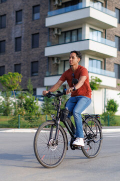 young man riding an e-bike on a sunny day near modern buildings in a city