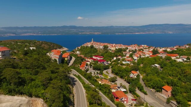 Aerial view of Vrbnik city rooftops and historic church tower from drone