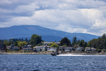 Fototapeta premium Coastal Waterfront Homes With Speedboat Off Sidney, Vancouver Island, BC, Canada and Mountain Clouds