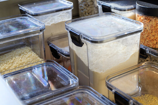 Clear plastic containers filled with flour and grains. Storing dry goods in airtight containers in a well-organized kitchen cabinet drawer