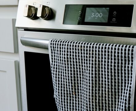 Man setting digital clock time on kitchen microwave stove appliances, representing changing clocks - daylight savings time, spring forward, fall back