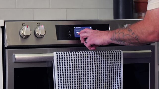 Man setting digital clock time on kitchen microwave stove appliances, representing changing clocks - daylight savings time, spring forward, fall back