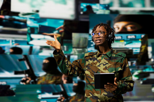 A panicked army officer points at a screen showing hostile forces while a communication specialist reacts to the threat on a tablet in a command center.
