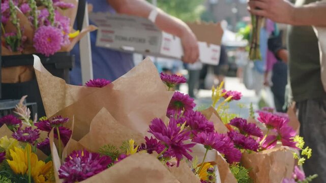 people linger beside pink flowers for sale at Brooklyn farmers market