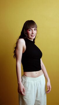 Young energetic woman dancing over yellow background