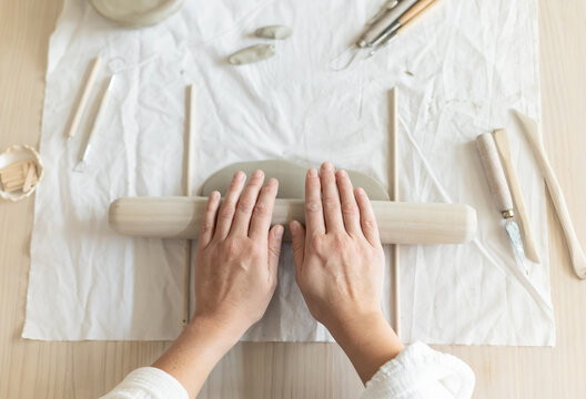 Women artist pottery shaping clay on a worktable with tools and cloth