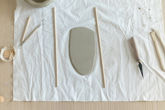 Women artist pottery shaping clay on a worktable with tools and cloth