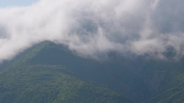 Foggy clouds moving over lush green mountains