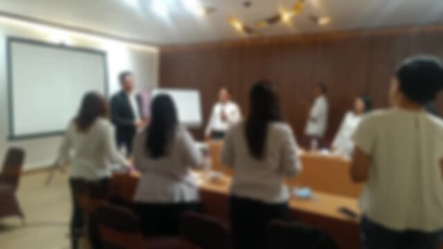 A blurred video of diverse group professionals actively engaged in a business meeting, with one person leading a presentation. The atmosphere is collaborative and dynamic.
