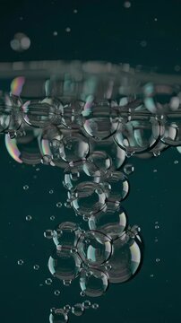 Close-up view of air bubbles rising through clear water against a dark background.