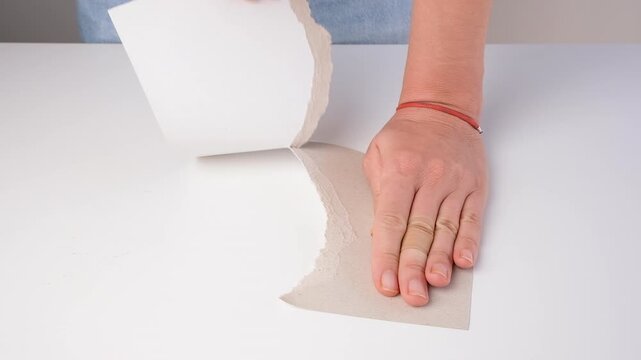 Close-up of a teacher tearing cardboard by hand for DIY craft project. Creative classroom demonstration encouraging handmade activities, imagination, learning and artistic skills