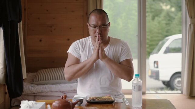 Japanese man saying 'itadakimasu' with a grateful prayer before eating a traditional meal at home