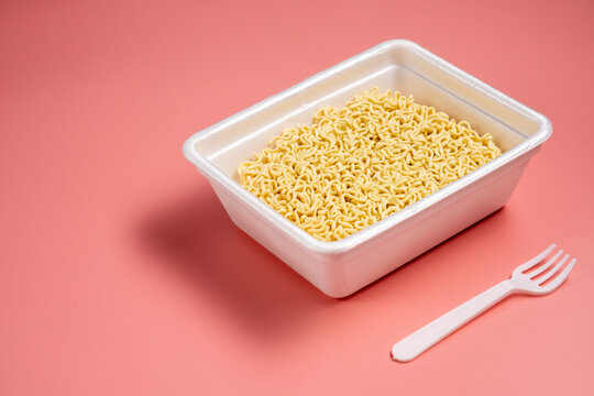 Instant noodles in styrofoam box on pink background
