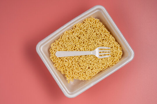 Instant noodles in styrofoam box on pink background