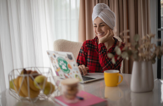 Smiling woman with hair towel using laptop at home