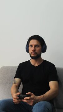 vertical detailed view of a latin gamer playing in concentrating attitude and using a wireless controller and headset