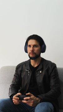 vertical detailed view of a man playing video games in concentrating attitude and using a wireless controller and headset