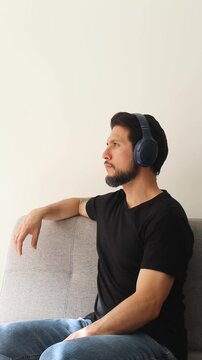 vertical detailed view of a male in a peaceful attitude sitting on a couch hearing something on a wireless headset