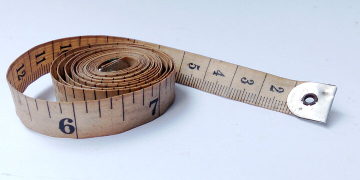 Vintage style tailor's measuring tape rolled up on a white surface.