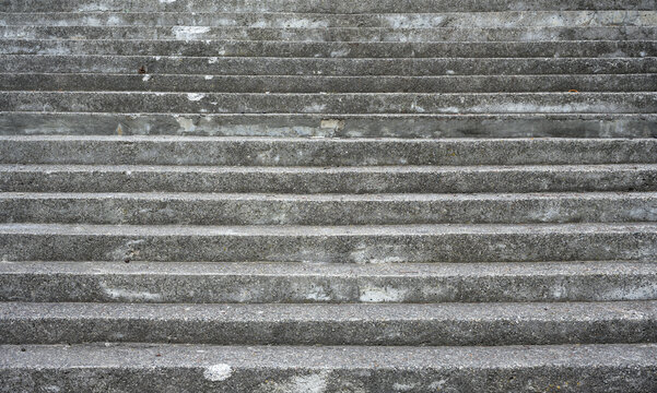 Weathered concrete stairs filling the frame. Close up of empty gray outdoor steps creating a repeating horizontal pattern. Urban architectural texture and background