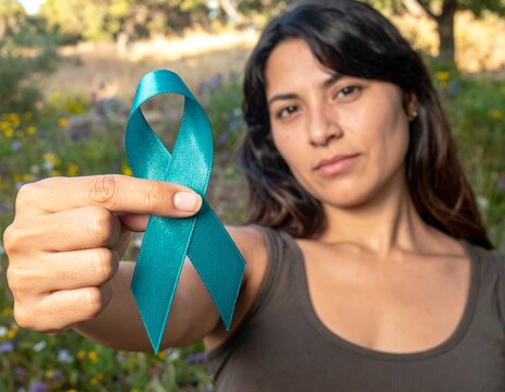 Teal ribbon awareness on woman's hand for Ovarian Cancer, Polycystic Ovary Syndrome (PCOS) disease, Post Traumatic Stress Disorder (PTSD), Tourette's Syndrome, Obsessive Compulsive Disorder (OCD)