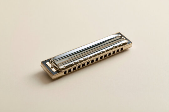 Matte metal harmonica on cream background blues music instrument