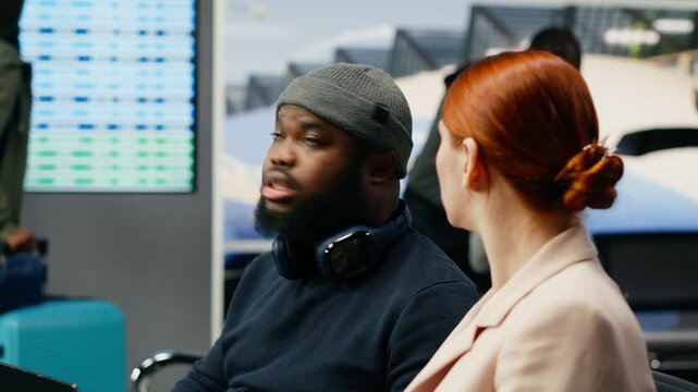 A diverse team of consultants types on a laptop in an airport lounge, analyzing data and preparing for an international business meeting during a delegated work trip before departure abroad.
