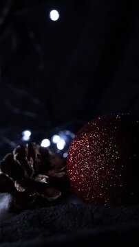 Una toma de cerca de unos adornos de navidad de varios colores con luces de navidad en un fondo negro. Video Vertical