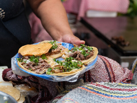 Close-up of hands preparing fresh street tacos with meat, onion and cilantro