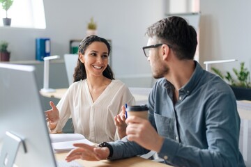 Obraz premium Smiling Young Woman And Man Communicating At Office, Engaged In Discussion Over Ideas. Collaborative Atmosphere In Modern Workspace, Fostering Creativity And Teamwork In Business Setting.