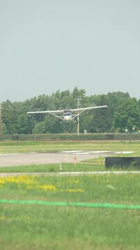 Small single engine Cessna 172 aircraft battles heavy crosswind while landing at regional airport runway near suburban homes