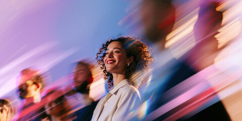 Obraz premium Optimistic Young African Professional Woman Looking Ahead Through Blue Pink Pastel Crowd Motion