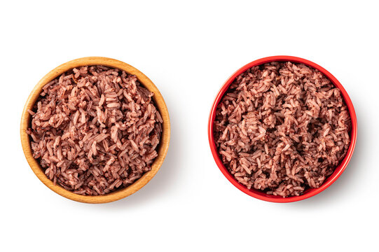 Top view of cooked organic Riceberry rice served in a natural wooden bowl and a vibrant red ceramic bowl, isolated on white. Perfect for healthy eating and nutrition concepts.