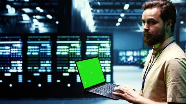 Engineer checks electronics with a laptop mockup in a data center, keeping the green screen display ready for screen replacement and post production during server check chroma key.