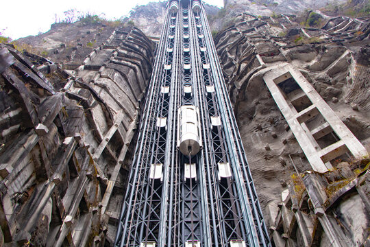 Glass capsule elevator structure mounted on steep mountain cliff, show advanced engineering breathtaking vertical transportation technology. Scenic lift offers dramatic of rugged rock formations.