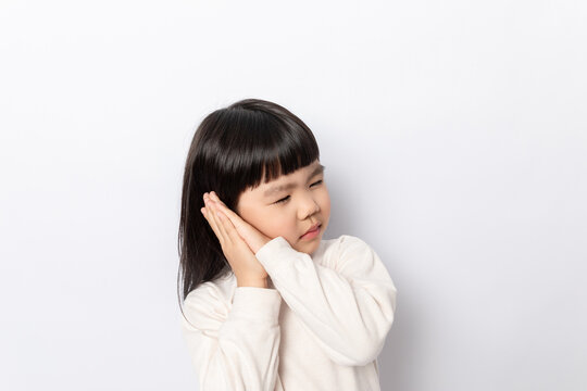 A little girl pretending to sleep against a white background