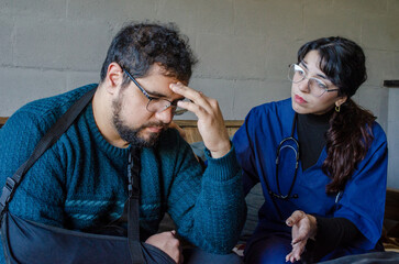 Fototapeta premium Sad injured man with arm sling receiving bad medical news from female doctor