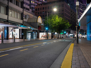 Obraz premium Car background, automotive backplate, central business district road featuring retail shops at night