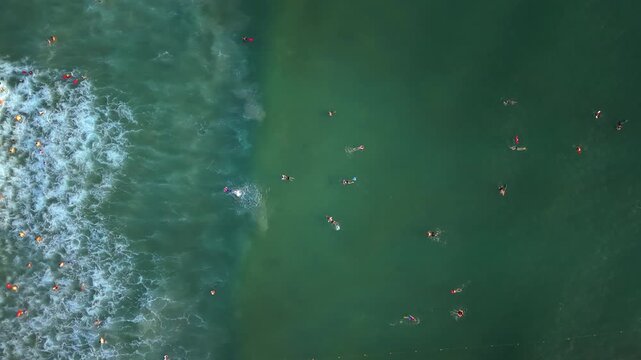 Vertical drone footage performing a smooth 360-degree rotation above emerald waves and swimmers at My Khe Beach in Da Nang, Vietnam. Dynamic aerial perspective with tropical coastal scenery.