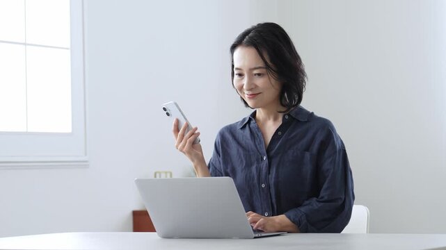 パソコンとスマートフォンを使う中高年女性