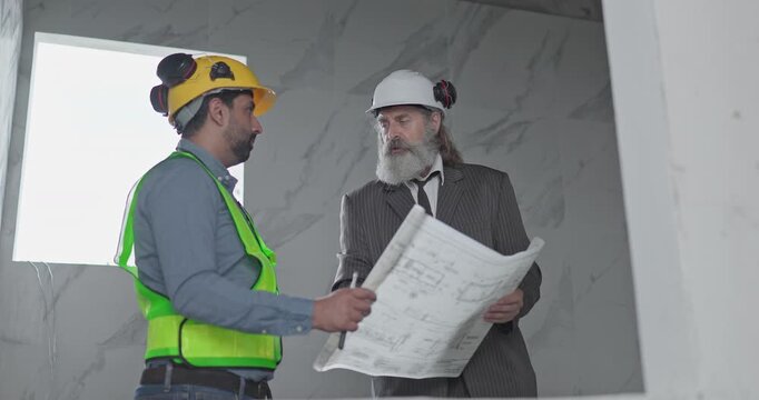 Engineer and businessman reviewing blueprint construction plans at house building site