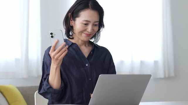 パソコンとスマートフォンを使う中高年女性