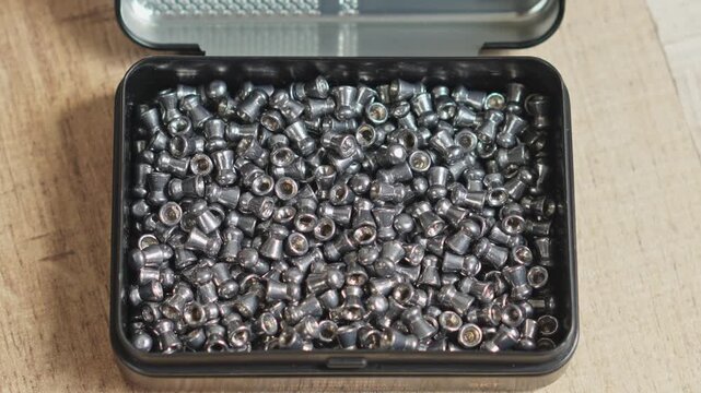 Close-up of metallic air rifle ammunition pellets falling to small storage containervideo slow motion concept