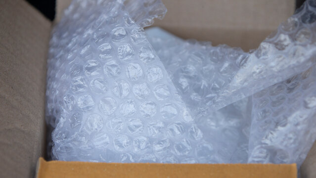 Close up of plastic bubble wrap inside a cardboard box for shipping.Close-up shot of clear plastic bubble wrap packaging material placed inside an open cardboard box.