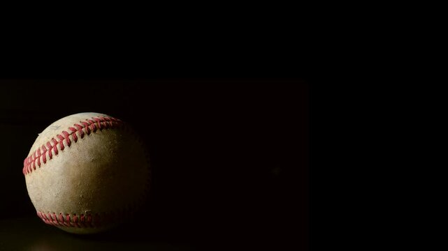 A well worn baseball rotating isolated against a black background. Sports or game ball concept with copy space.