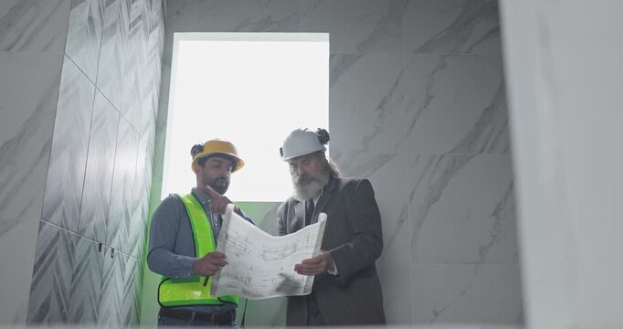Engineer and businessman reviewing blueprint construction plans at house building site