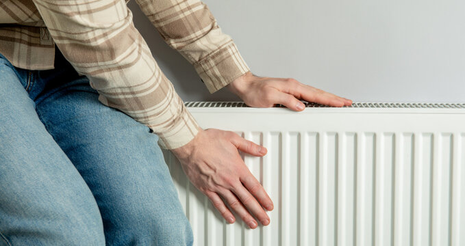 Heating season. Person checks radiator temperature for optimal warmth during heating season