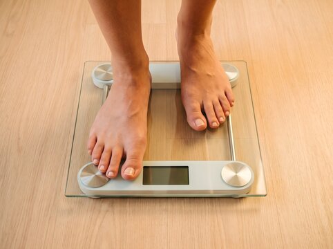 Bare feet of a person standing on a digital glass scale to measure weight