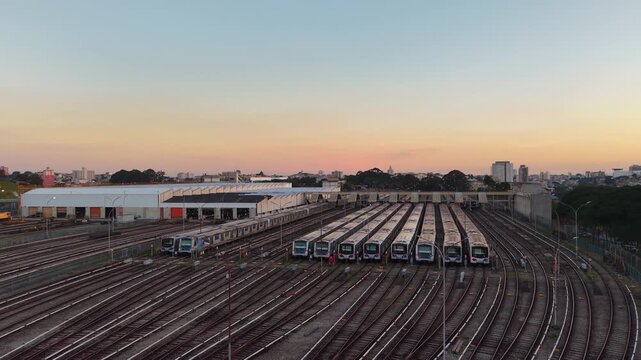 Aerial view of metro trains parked in a large railway depot at sunset