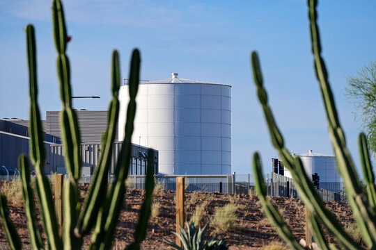 Data center with water storage tanks viewed through desert cacti, illustrating AI infrastructure, cloud computing, utility systems, and sustainable facility design